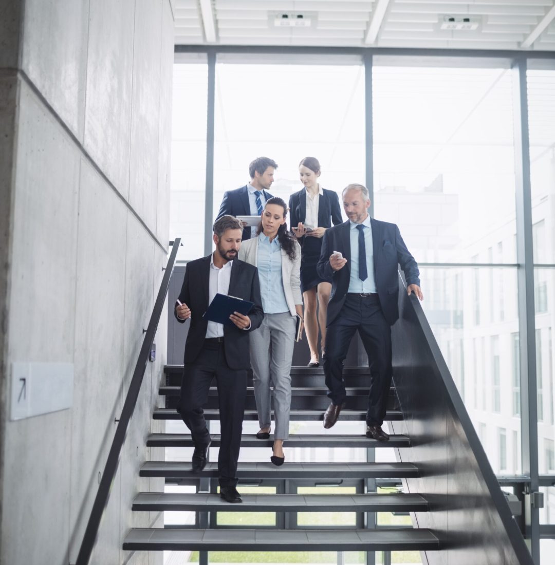 confident businesspeople standing on staircase in office